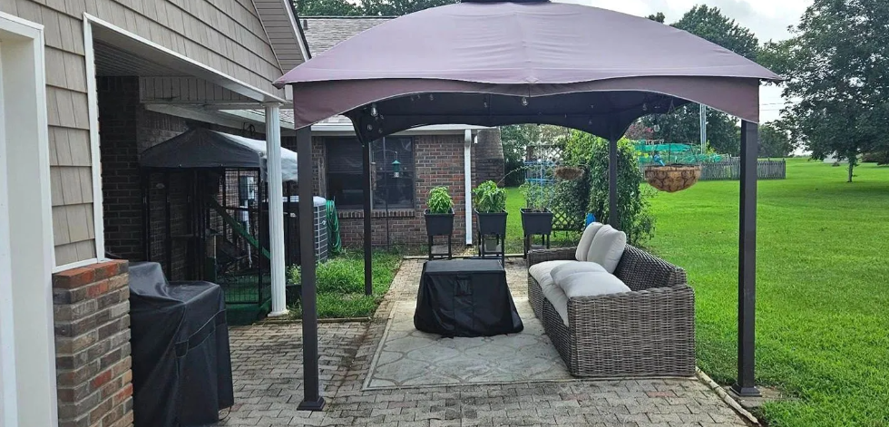 Backyard patio with covered seating, outdoor sofa, fire pit, and grill beside a house