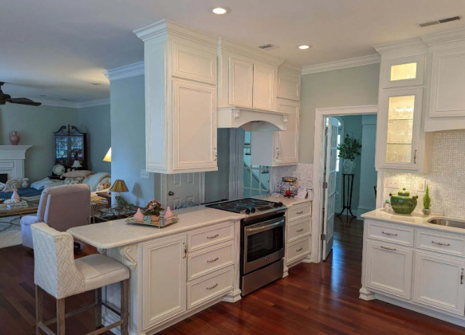 Bright white kitchen with island, stove, cabinets, and hardwood floors in an open-plan home