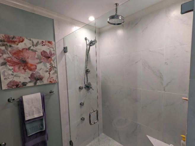Modern bathroom shower with glass enclosure, chrome fixtures, and gray marble-style walls