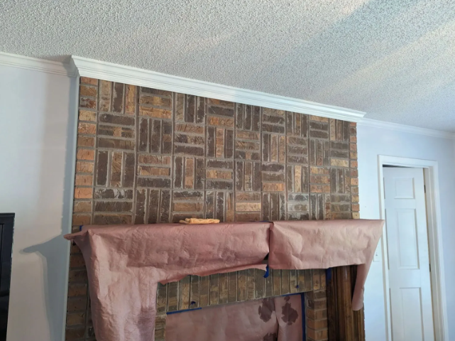 Brick-pattern fireplace wall with white trim and a draped mantel in a light-colored room