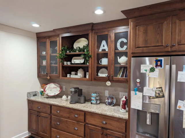 Kitchen with wooden cabinets, countertop decor, and stainless steel refrigerator under recessed lights