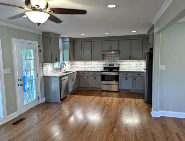 Bright modern kitchen with gray cabinets, stainless appliances, white tile backsplash, and hardwood floors