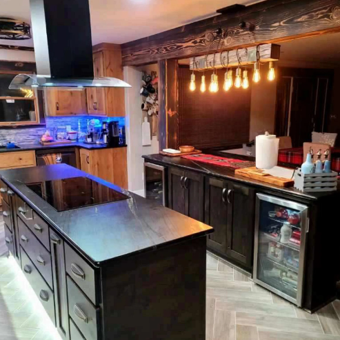 Modern kitchen with dark cabinets, stainless island, wine fridge, and hanging pendant lights