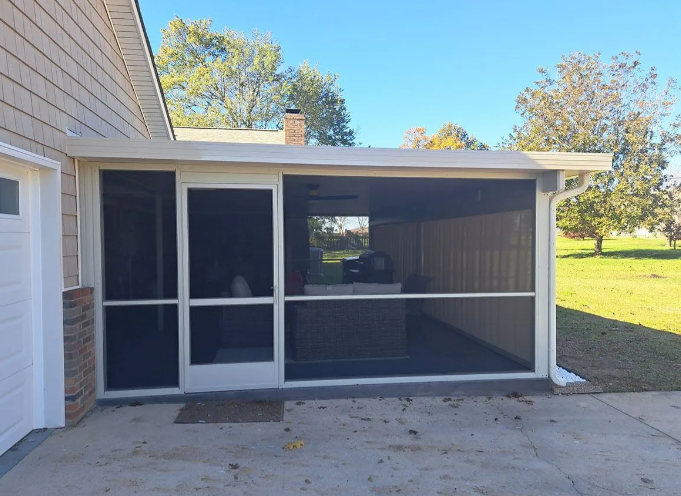 Screened patio enclosure attached to a house, with white trim and sliding glass doors.