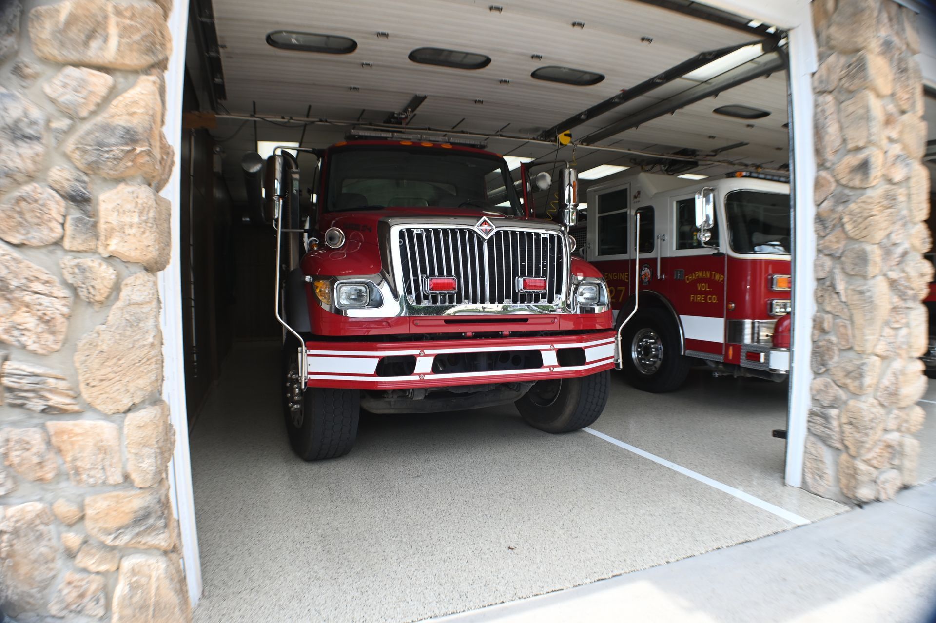 A fire truck is parked in a garage next to another fire truck.