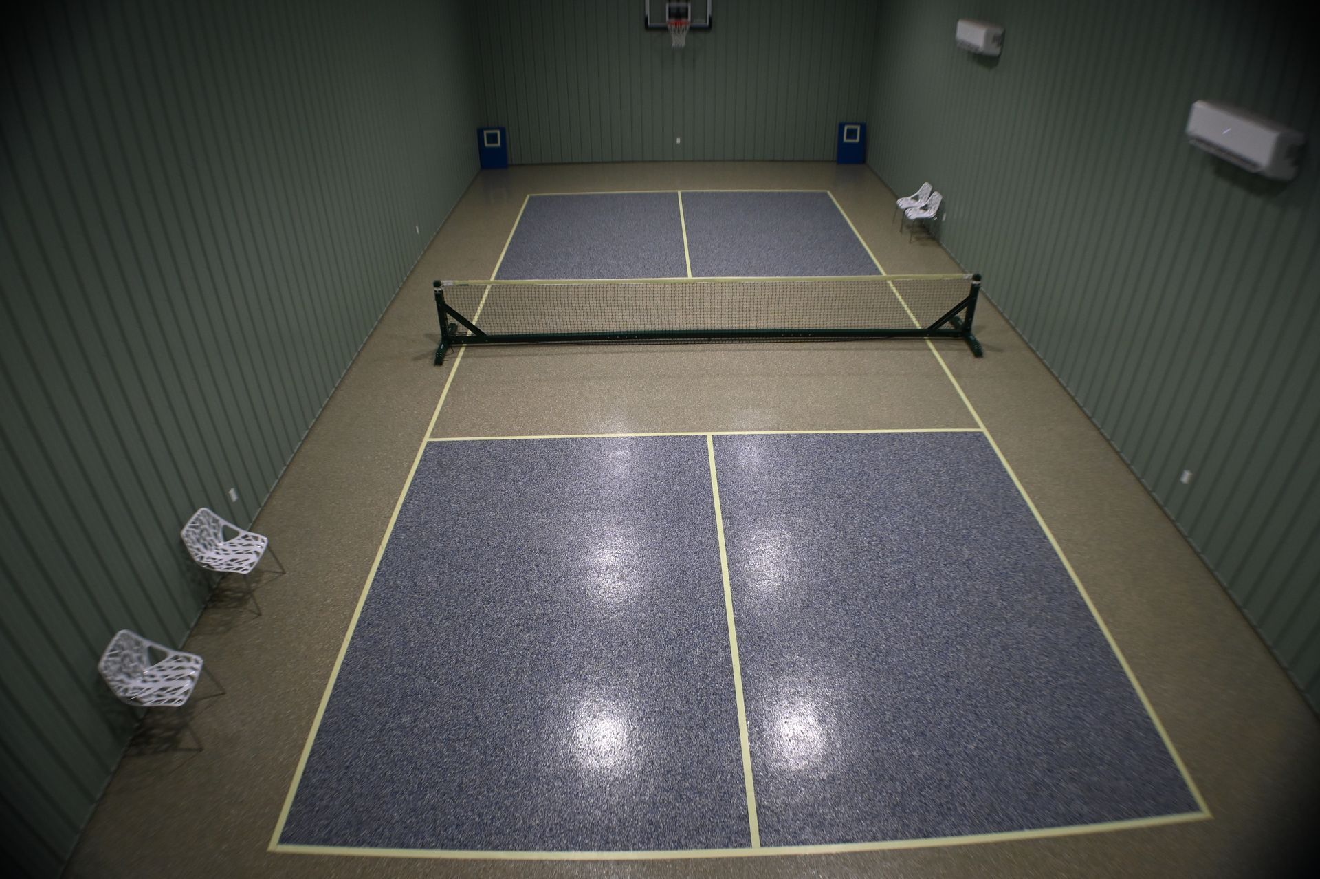 A tennis court with a basketball hoop in the background