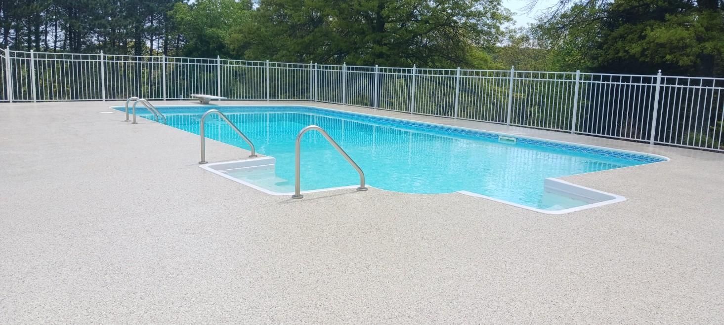 A large swimming pool surrounded by a fence and trees.