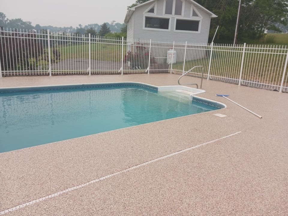 A large swimming pool with a fence around it and a house in the background.