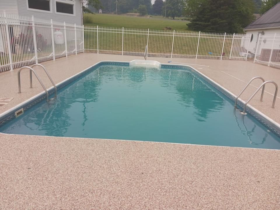 A large swimming pool with a fence around it and a house in the background.