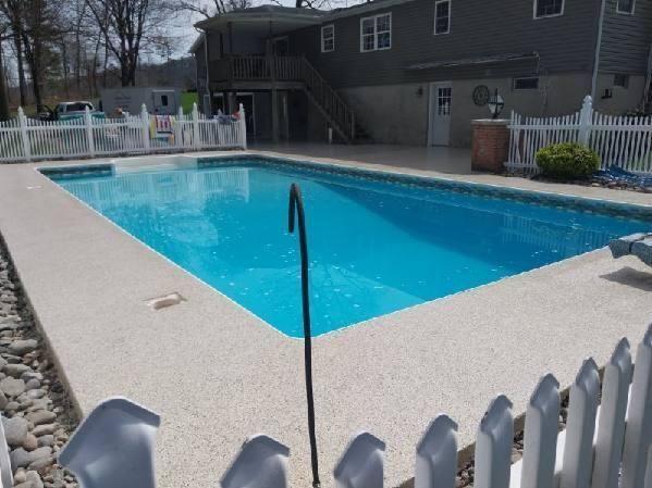 A large swimming pool is surrounded by a white picket fence.