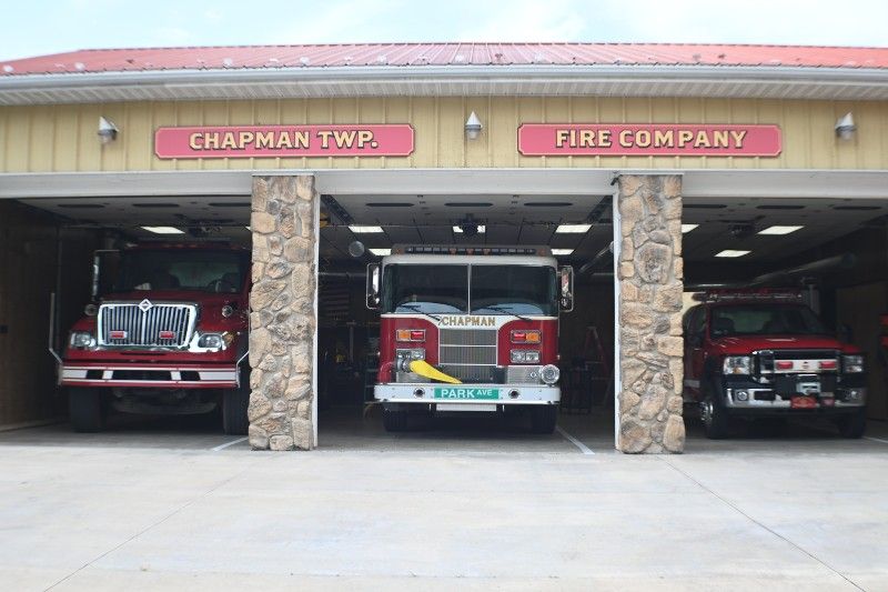 Three fire trucks are parked in front of a fire station