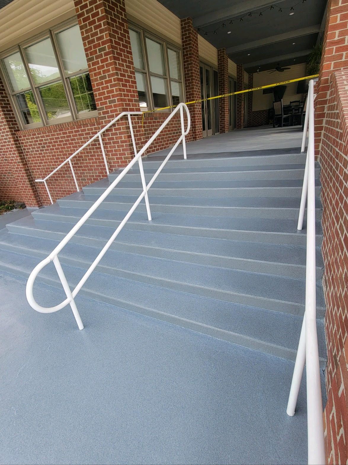 A set of stairs with a white railing and a brick building in the background