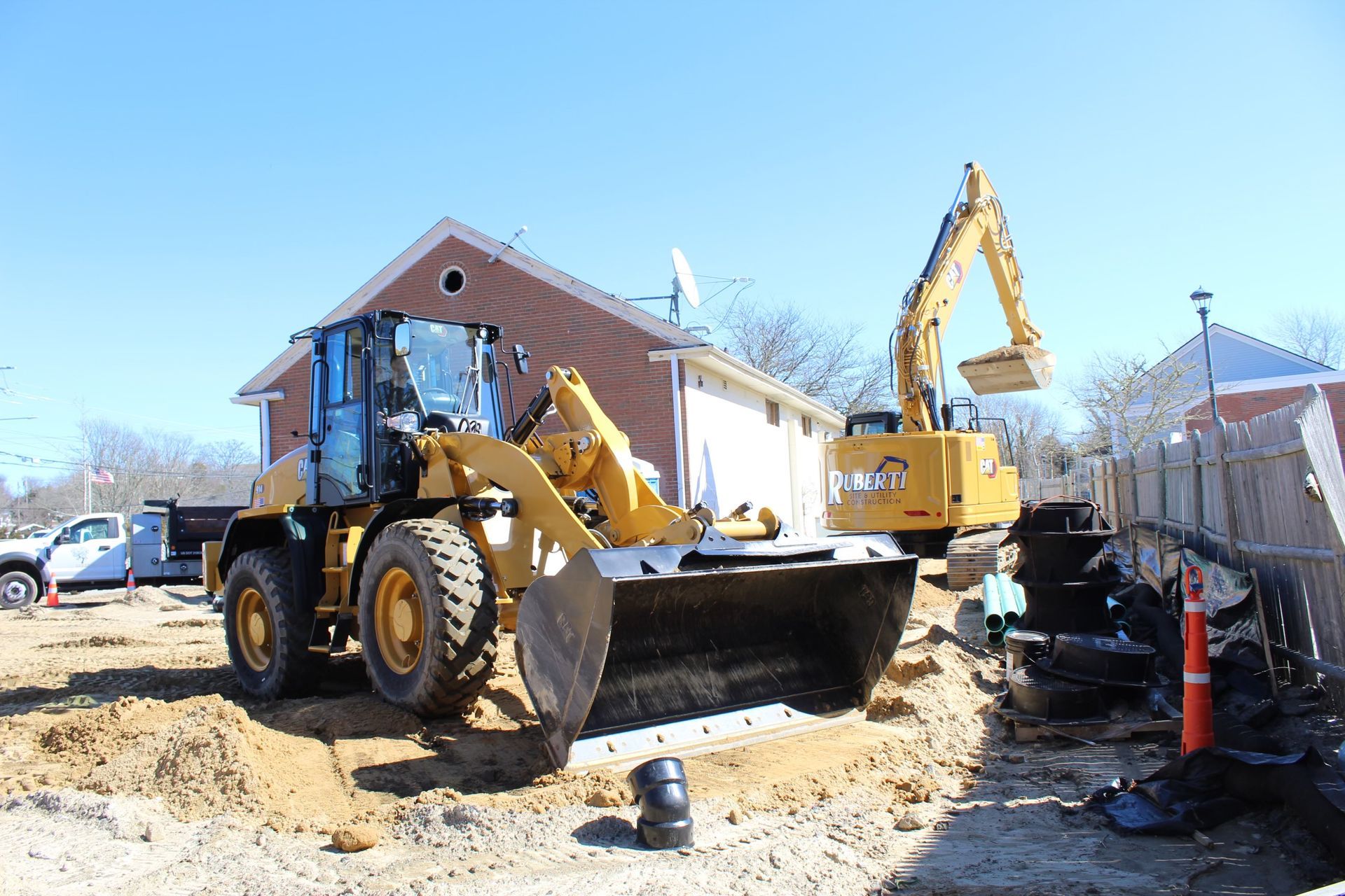 Yellow construction vehicles digging near a residential building.