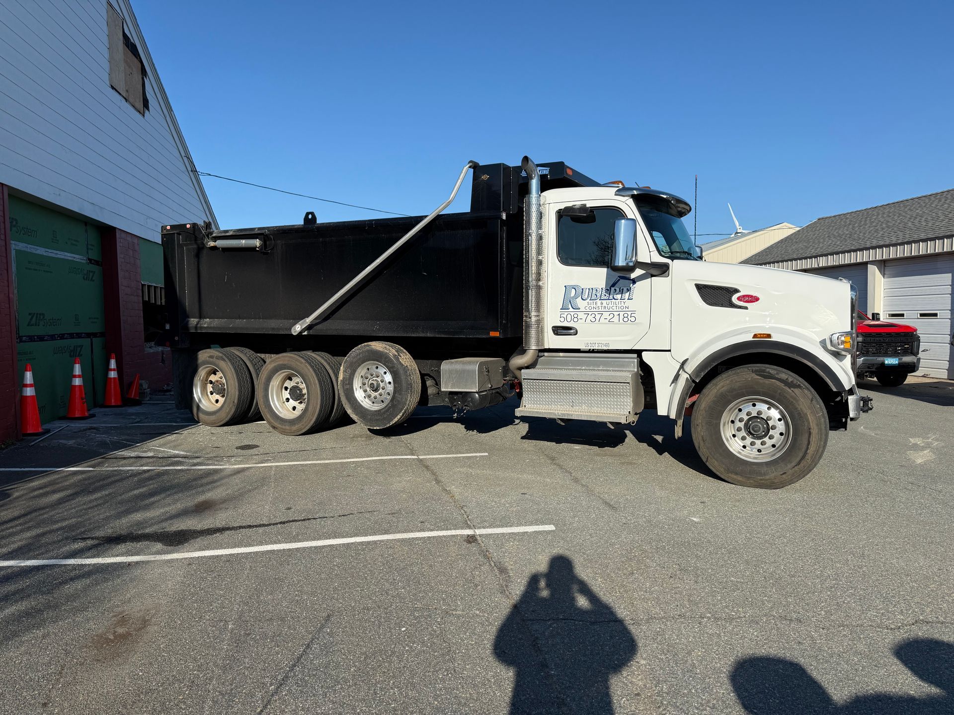 White dump truck parked next to a building on a sunny day.