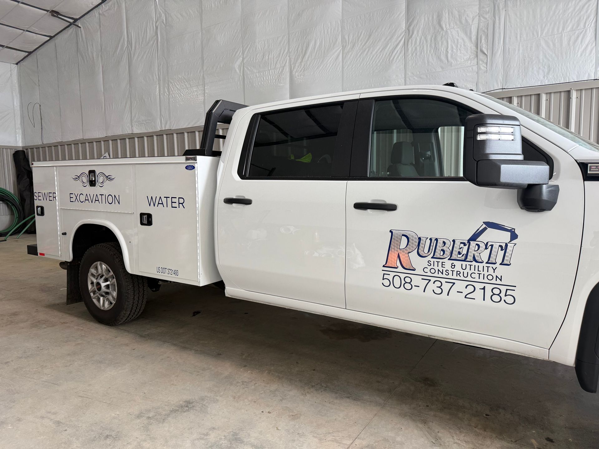 White work truck with toolboxes and business logo.