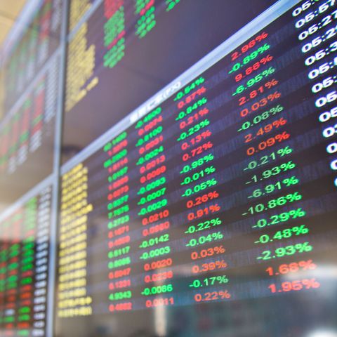 Stock market display boards with red and green price changes and percentage data.
