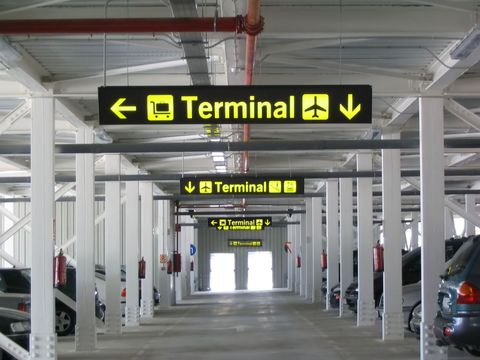 Airport parking garage with repeated overhead signs pointing to the terminal.