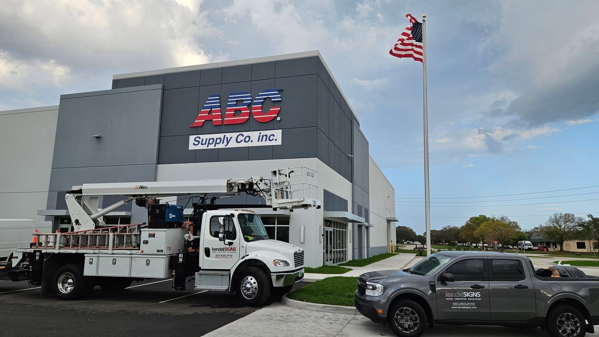 ABC Supply Co. storefront with a service truck, parked SUV, and an American flag outside