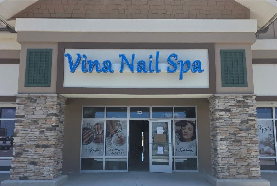 Storefront of Vina Nail Spa with blue sign and glass entrance on a shopping plaza facade