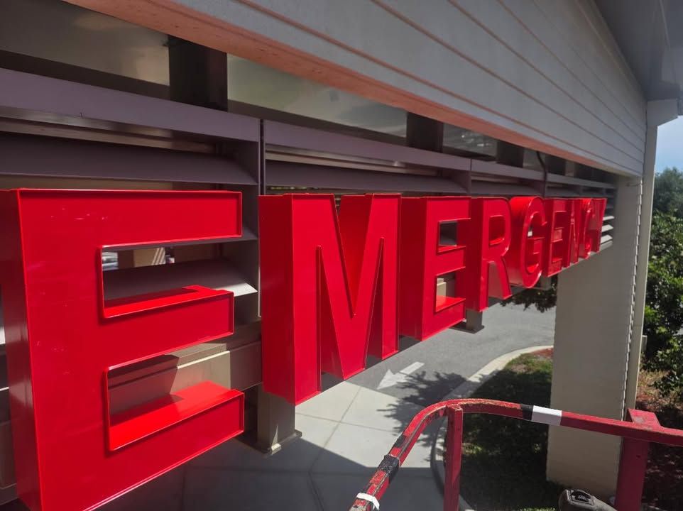 Bright red MERGE sign on a building exterior, viewed at an angle under a covered walkway.