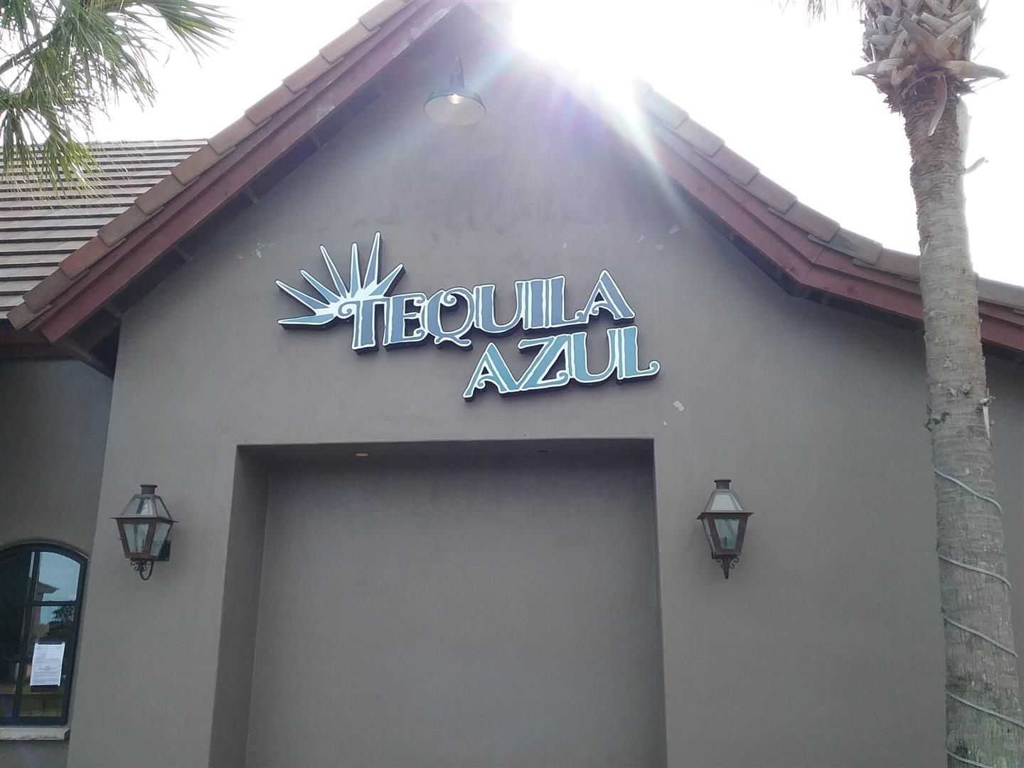 Tequila Azul sign on a gray stucco building with tiled roof and palm tree
