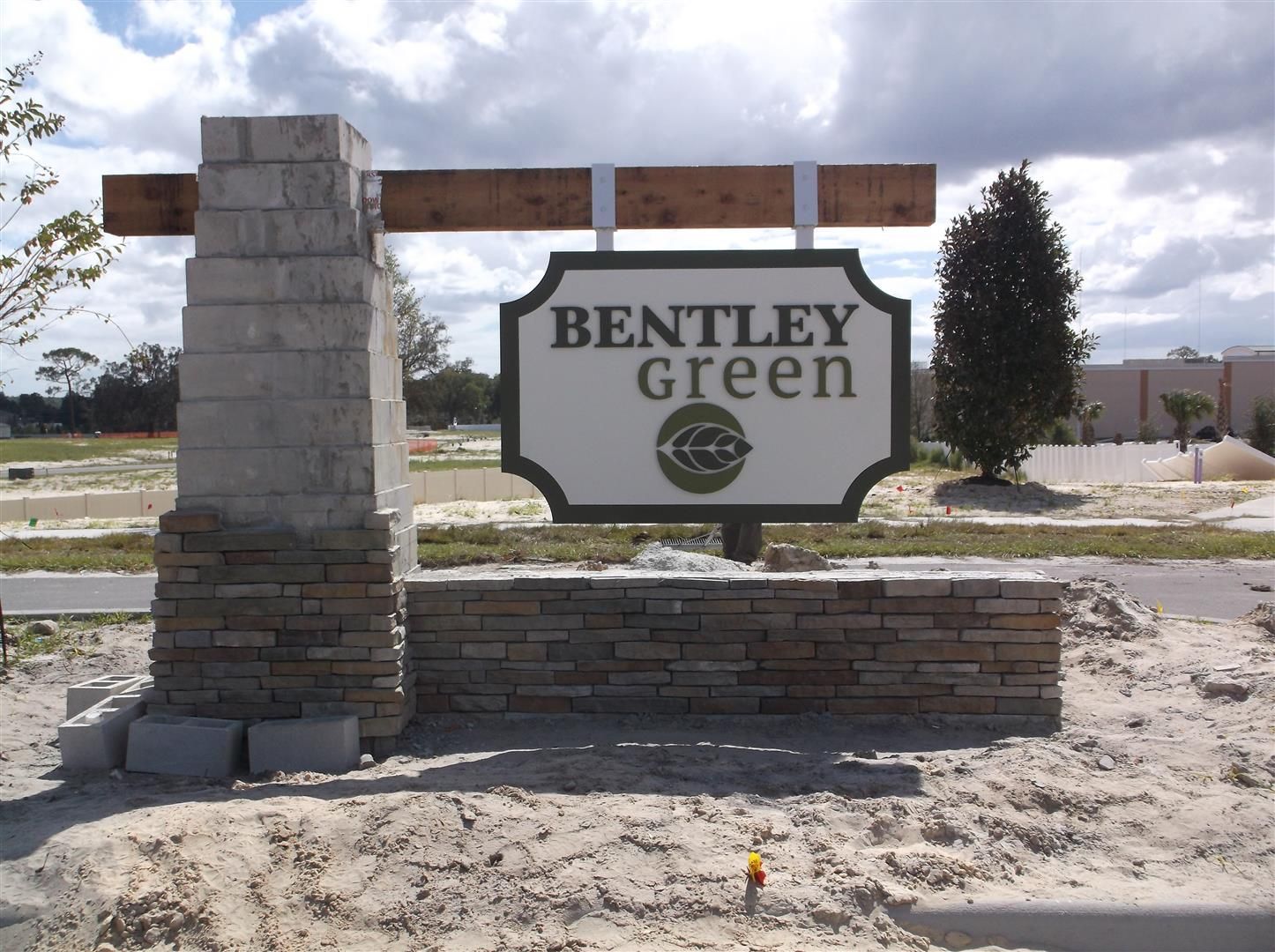Bentley Green entrance sign on a stone and brick monument beside a road and grassy field