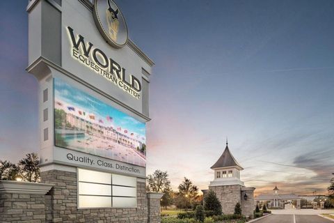World sign at entrance to a resort community at sunset, with stone tower and road in the background