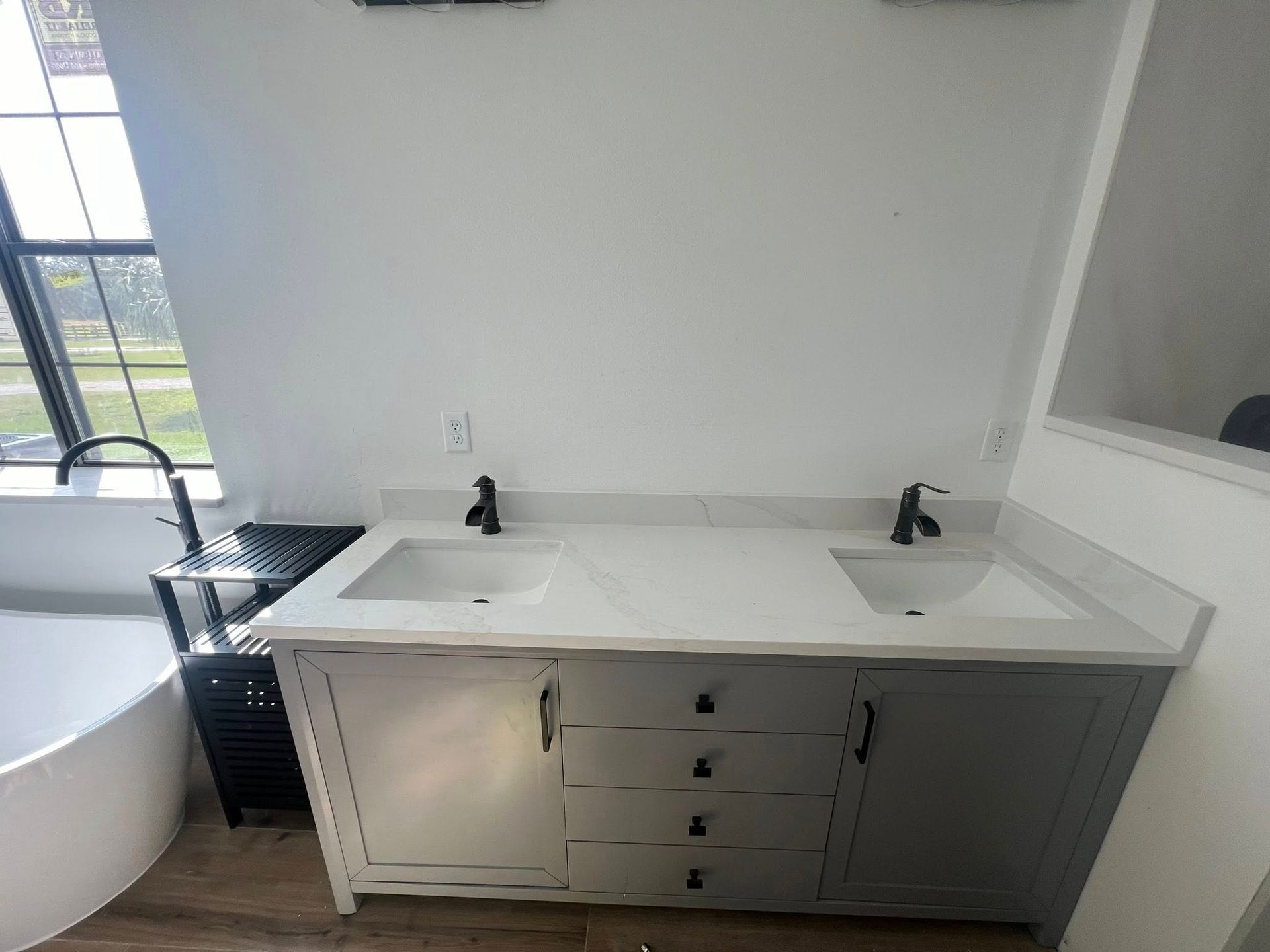 Gray double vanity with white countertop, black faucets, and rectangular sinks in a bathroom.