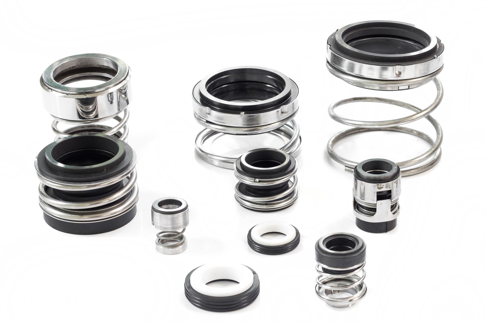 Assorted metal and black rubber mechanical seals and springs on a white background