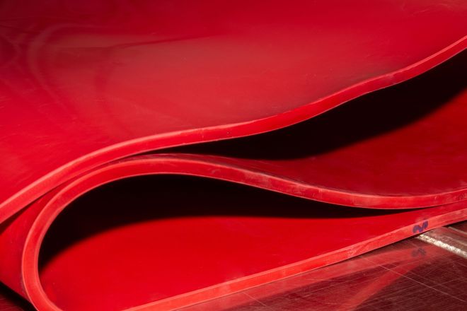 Abstract red curved metal or plastic surfaces with glossy reflections and layered waves