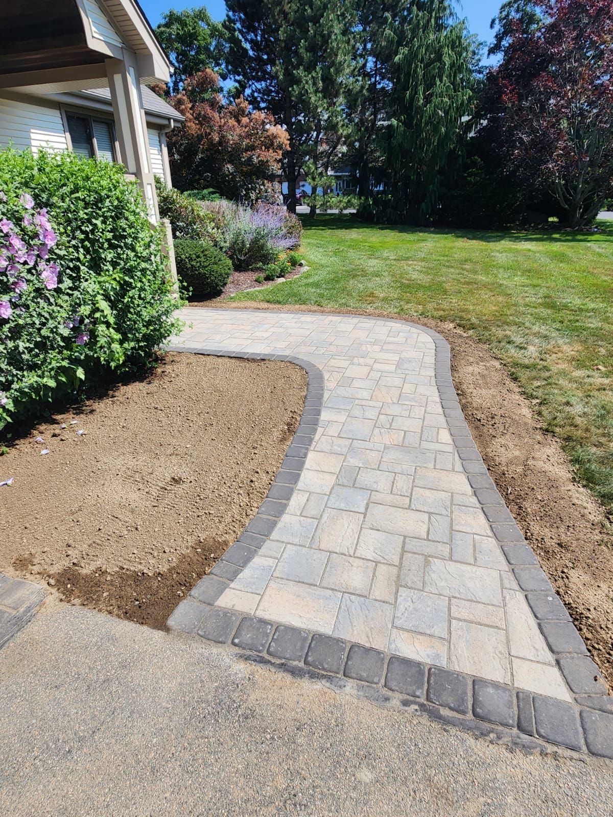 a lush green lawn with flowers and bushes in front of a house