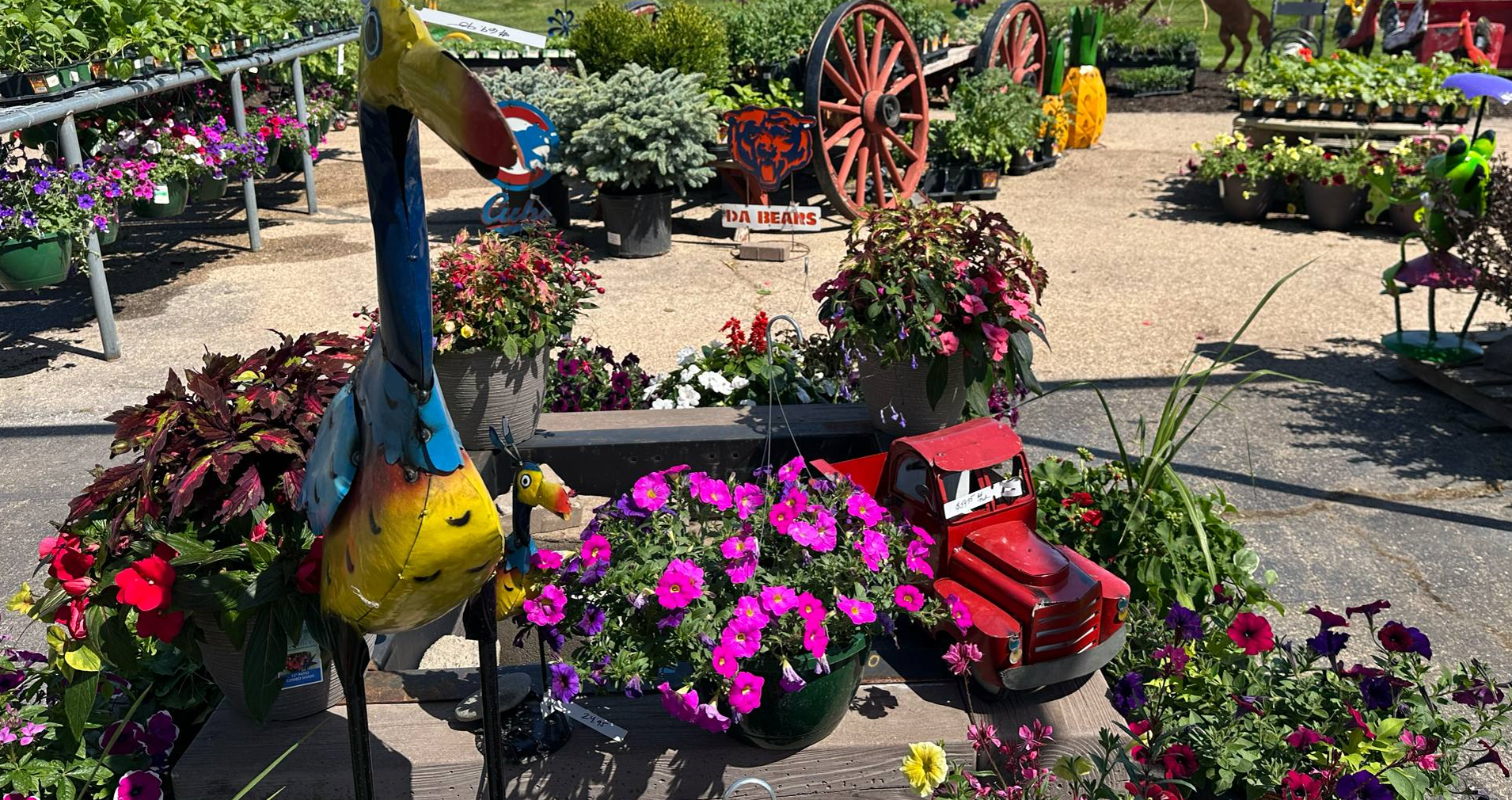A yellow watering can filled with flowers is hanging from a pole.