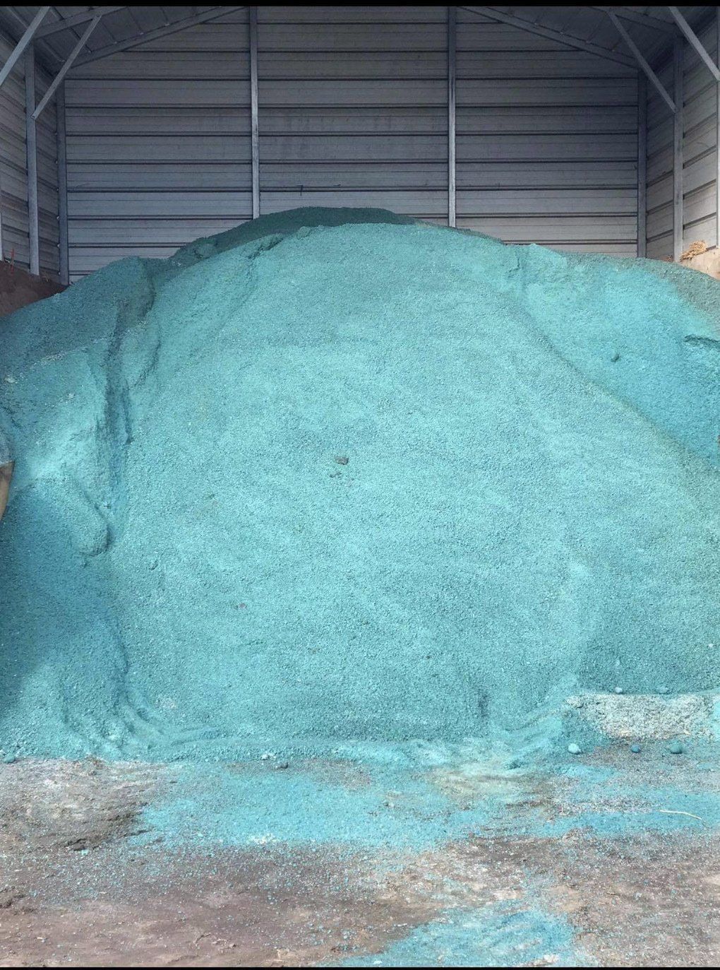 A large pile of blue gravel is sitting inside of a building.
