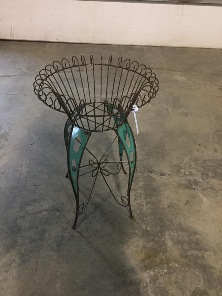 A small table with a basket on top of it is sitting on a concrete floor.