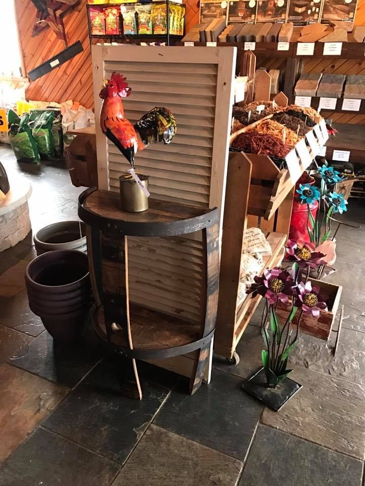 A rooster statue is hanging on a wooden shutter in a store.