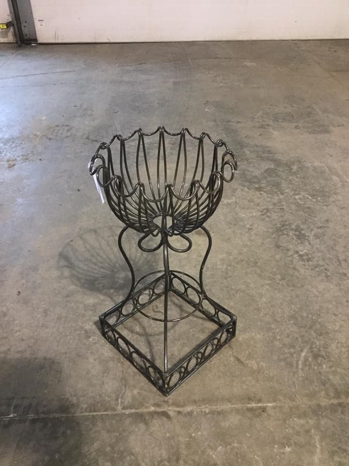 A wrought iron basket is sitting on top of a concrete floor.