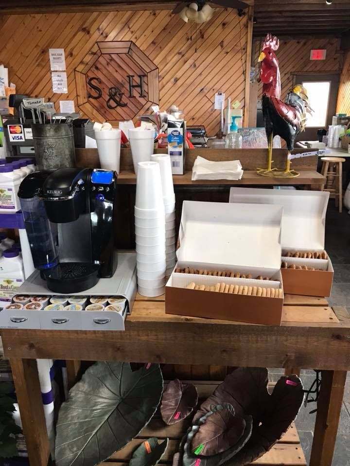 A wooden table with a coffee maker and cups on it.