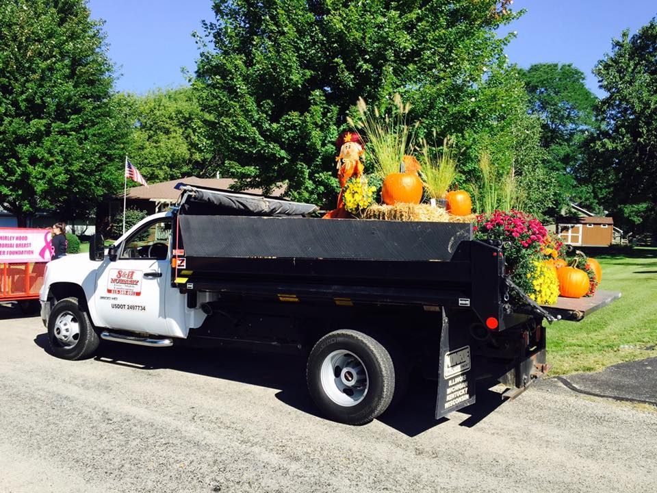 A dump truck with pumpkins and flowers in the back