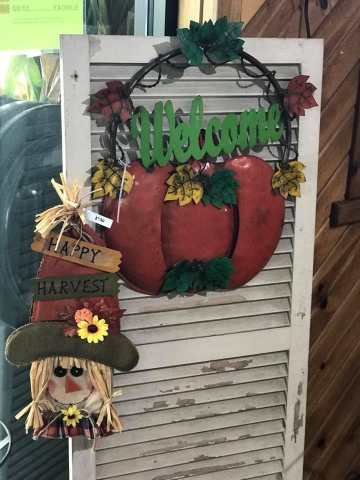 A scarecrow with a sign that says happy harvest