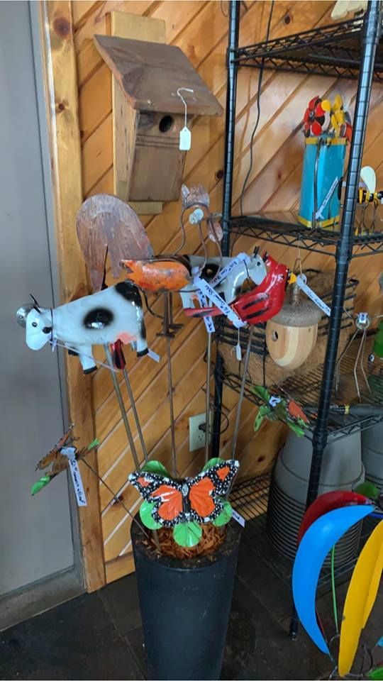 A butterfly is in a pot next to a cow and a birdhouse.