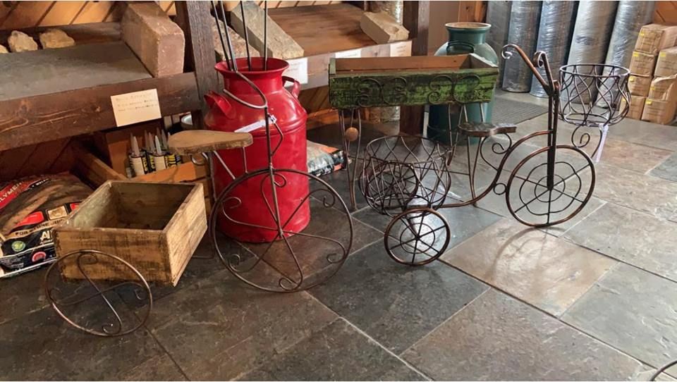 A red milk can is sitting next to a wooden box and a metal bicycle.
