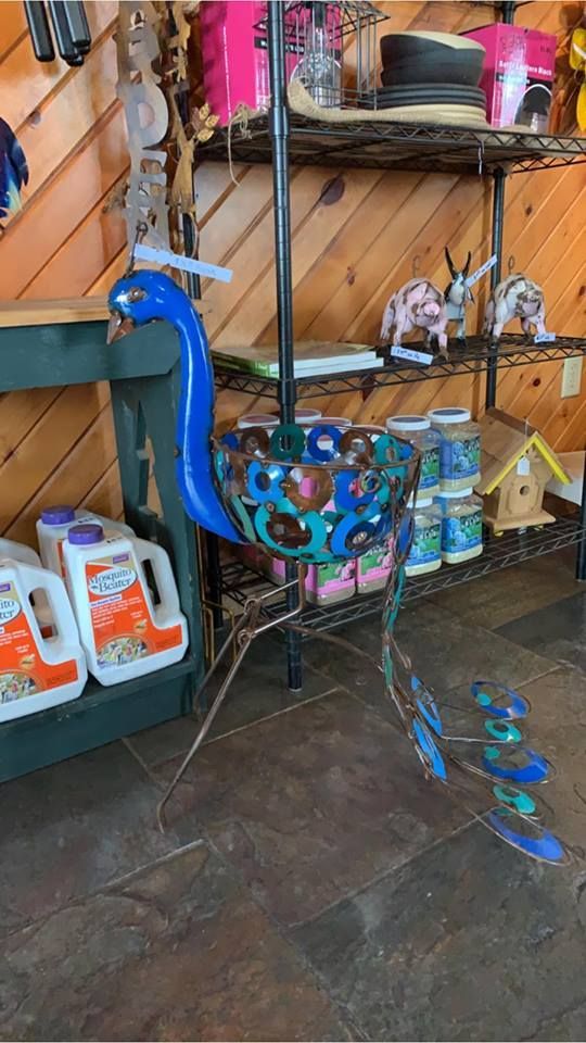 A blue peacock is sitting on a metal stand in a store.