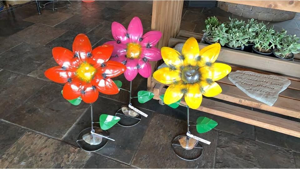 Three flowers made out of plastic bottles are sitting on a tiled floor.