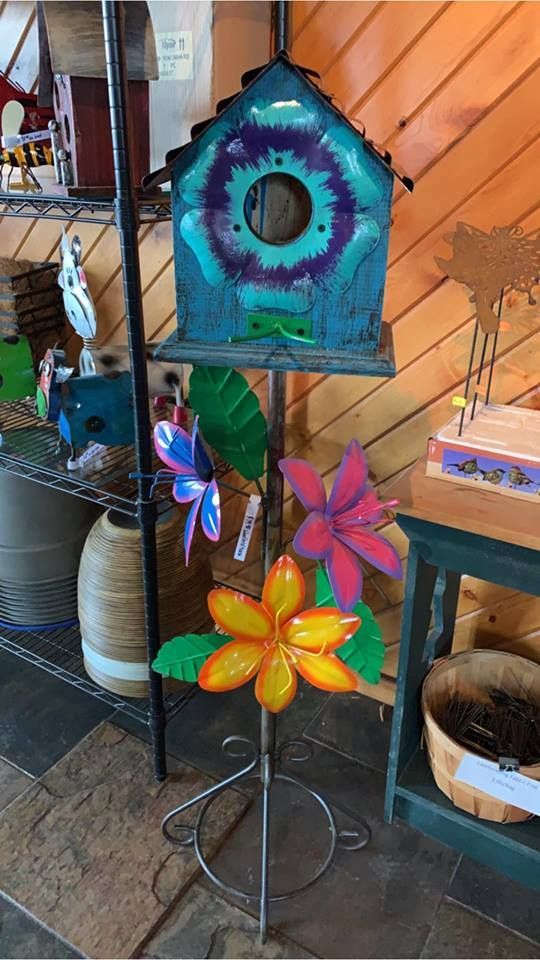 A birdhouse is sitting on top of a metal stand next to a flower.