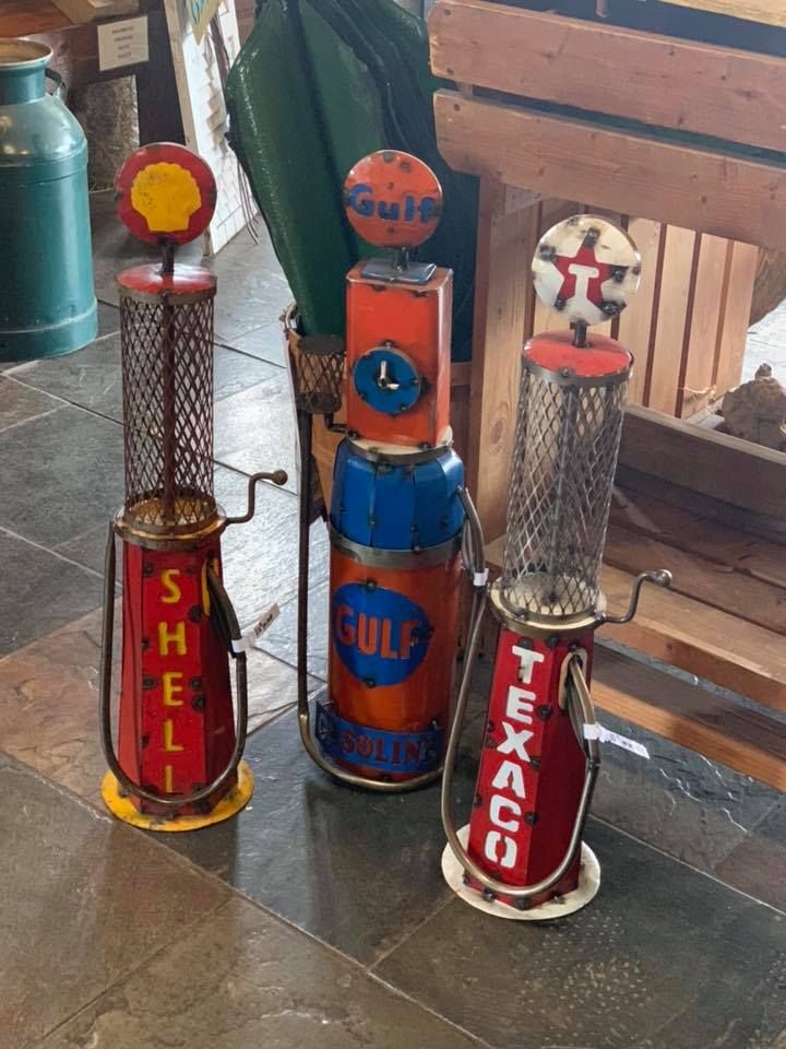 Three antique gas pumps are sitting on a tiled floor.