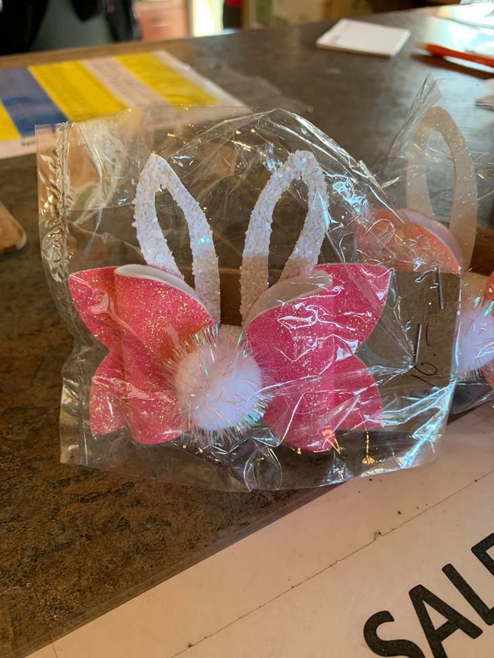 A pink and white bow with bunny ears is in a plastic bag on a table.