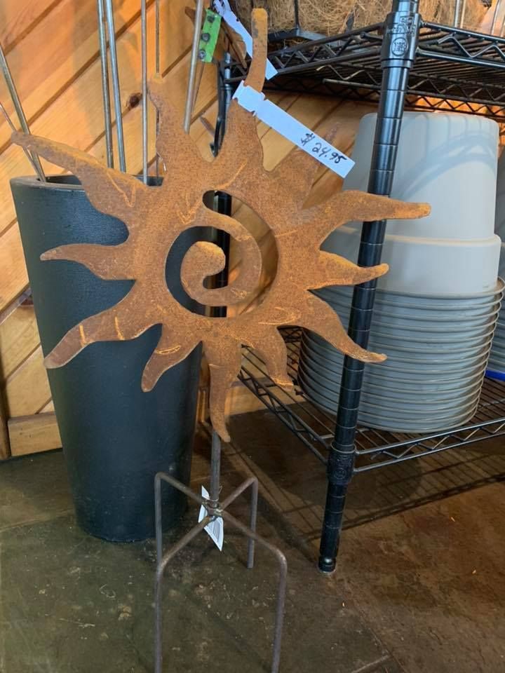 A sun shaped sculpture is sitting next to a black pot.