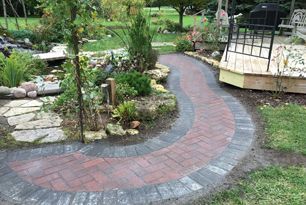 A brick walkway leads to a gazebo in a garden.
