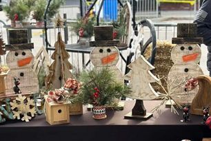 A table topped with wooden snowmen and Christmas trees.