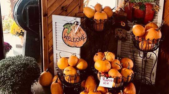 A bunch of pumpkins are sitting on a table in front of a welcome sign.